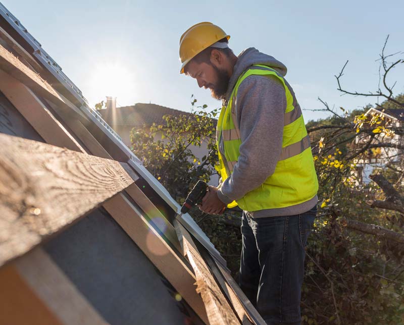 man-working-on-roof-with-a-drill